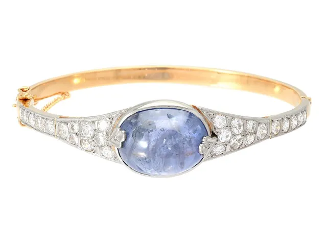 ARMRING, 18K guld/vitguld, cabochonslipad safir ca 25,00 ct, gammal- och briljantslipade diamanter ca 2,00 ctv, ca TW-Cr/VS-P, Stockholm 1950, stl 56x52 mm, vikt 27,0 g, säkerhetskedja, tennlödningar, en del skev, safiren har naturliga håligheter och inneslutningar som når ytan, enstaka diamanter har nagg och skador.