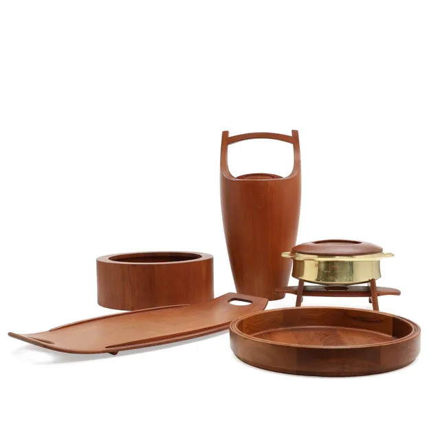 A selection of teak serving pieces comprising salad bowl, ice bucket with red plastic liner, two trays and brass serving pan with teak lid and stand. Stamped Dansk Designs Danmark IHQ. Salad bowl H. 13. Diam. 33. Ice bucket H. 48. Serving pan incl. stand H. 18. Diam. 24. Circular tray diam. 36.5. Oblong tray 60 cm. (5)