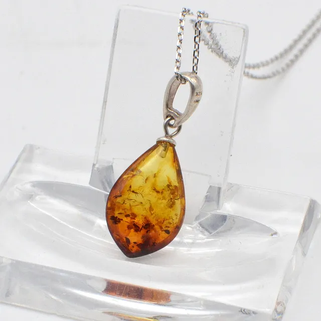DESIGNERCOLLIER MIT EINEM BERNSTEIN-ANHÄNGER MIT BLATTEINSCHLÜSSEN, TROPFENFÖRMIG UND POLIERT, ANKERKETTE AUS STERLINGSILBER, STUDIOSTEMPEL "BB", VINTAGE.