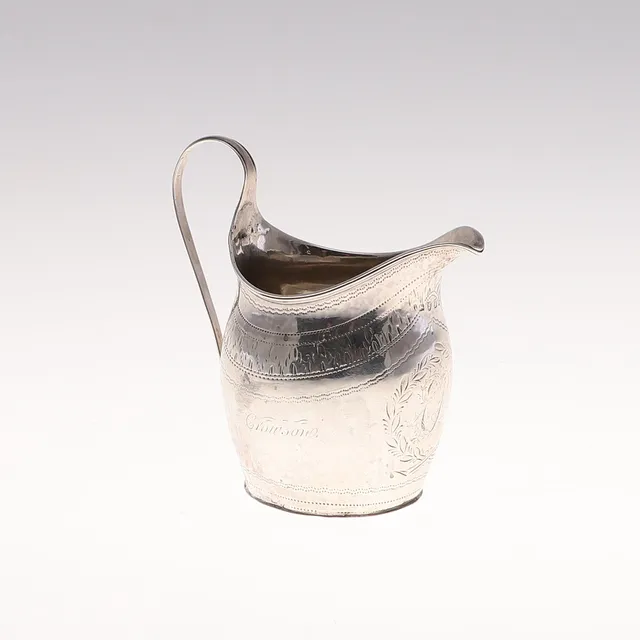 A GEORGE III SILVER HELMET SHAPED MILK JUG.