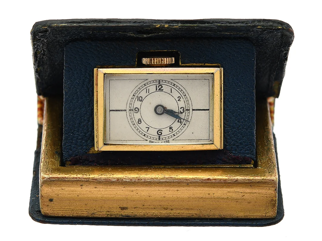 RESEUR, i form av en bok, 44,5 x 38,5 x 13 mm, Boett nr. 282582 / 123, bicolour/läder, manuell, plexiglas, skadad urtavla, ca 1950. — Klockor/Övriga klockor — Kaplans