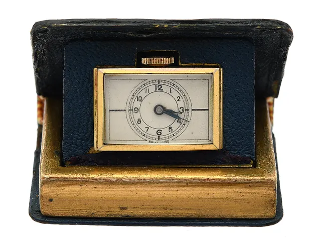 RESEUR, i form av en bok, 44,5 x 38,5 x 13 mm, Boett nr. 282582 / 123, bicolour/läder, manuell, plexiglas, skadad urtavla, ca 1950.