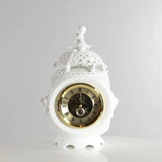 ARNOLD KROGH. “Helblonde”, sjældent urhus af hvid porcelæn, top med hvælvet blonde hvorpå dreng siddende med timeglas og seks kravlende snegle, herunder større snegl, sider med ringhanke i form af maskaroner, på hvælvet fodstykke. Udført og mærket hos Royal Copenhagen.
