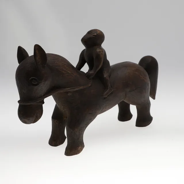 A CARVED WOODEN HORSE AND RIDER.