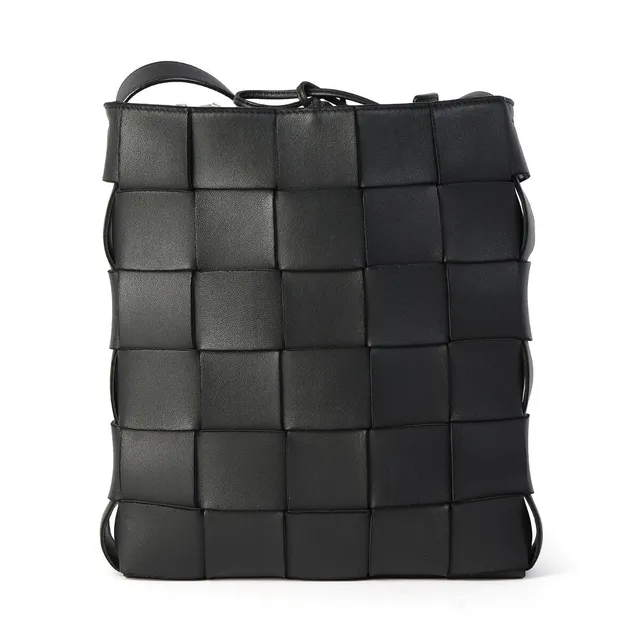 A “Cassette” bag of black woven leather with silver tone hardware, shoulder strap, one compartment with a tie ribbon and two interior pockets. H. 18 x W. 23 x D. 6 cm.
