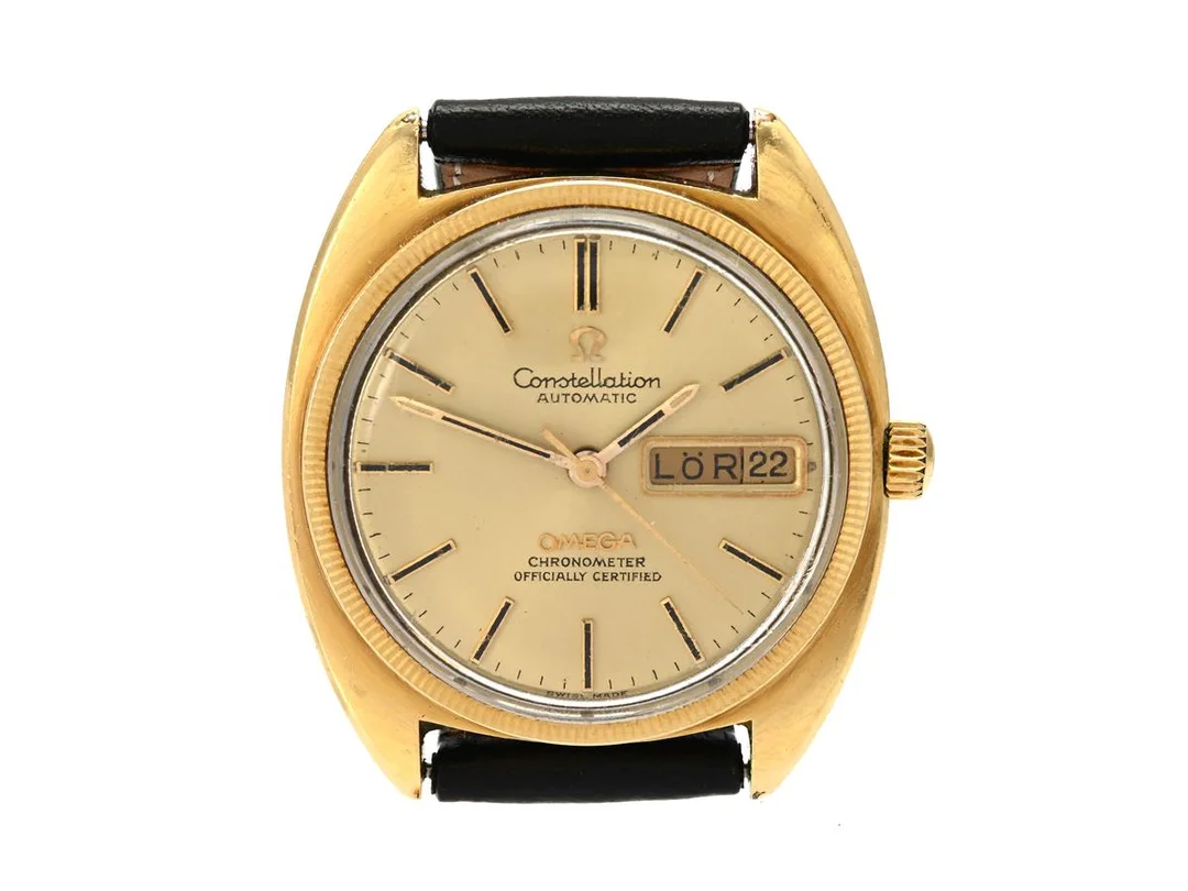 OMEGA, Constellation, "C", Chronometer, Cal 751, Serie nr. 32600104, Ref nr. CD 168.029, Boett nr. 168.029 (K.B), herrur, 35 mm, guld på stål, automatisk, plexiglas, dag (svenska), datum, servicebehov, räfflad glasring, skadad boett (se bild), läderband, ca 1970, box (ej komplett). — Klockor/Omega — Kaplans