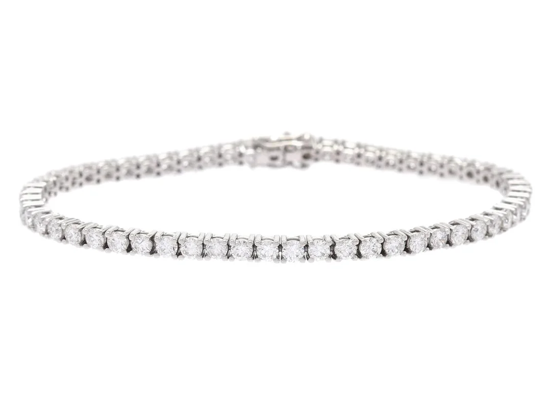 TENNISARMBAND, 18K vitguld, 55 briljantslipade diamanter ca 4,86 ctv, ca TW-TCr/SI-P, längd 17,5 cm, vikt 12,4 g, enstaka diamanter med nagg. — Smycken/Tennisarmband — Kaplans